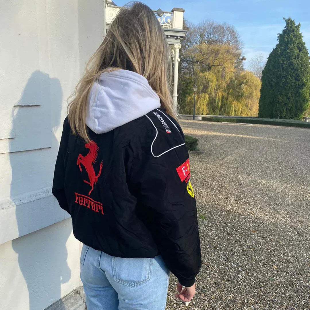 Person wearing a black Ferrari jacket with red logo outdoors.